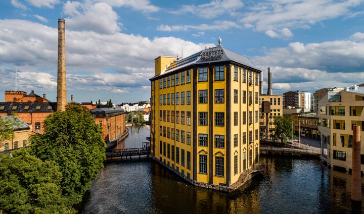 Gul flervåningsbyggnad som står mitt i ett vattendrag.