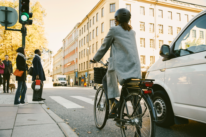 Bilden visar en kvinna på el-cykel i en stadsmiljö