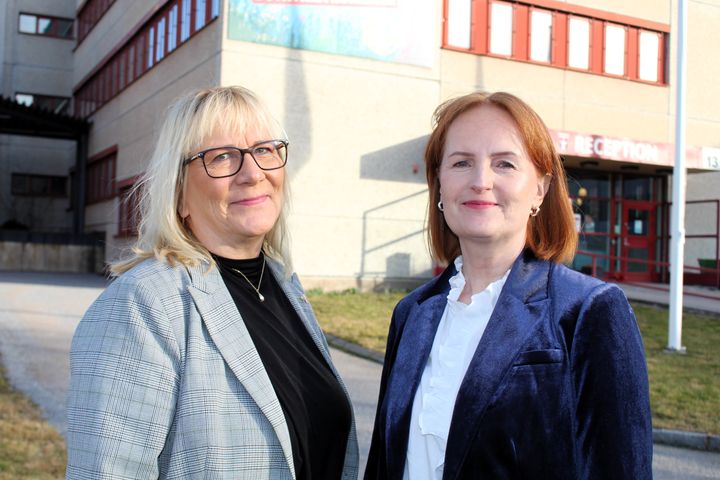 Två kvinnor står framför kommunhuset i Tumba en solig dag.