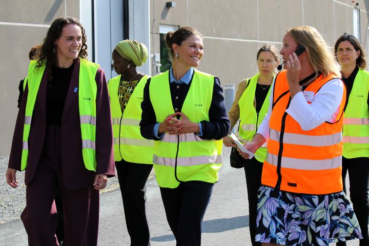 En grupp personer i reflexvästar går och samtalar utomhus.