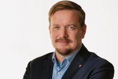 En man i kostym med en ljus bakgrund.