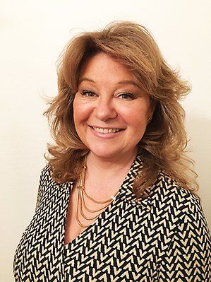 Bild%20p%E5%20en%20leende%20person%20med%20lockigt%20h%E5r%20och%20m%F6nstrad%20kavaj.