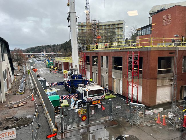 Byggarbetsplats%20med%20kranar%2C%20byggmaskiner%20och%20of%E4rdiga%20byggnader%20under%20en%20molnig%20himmel.