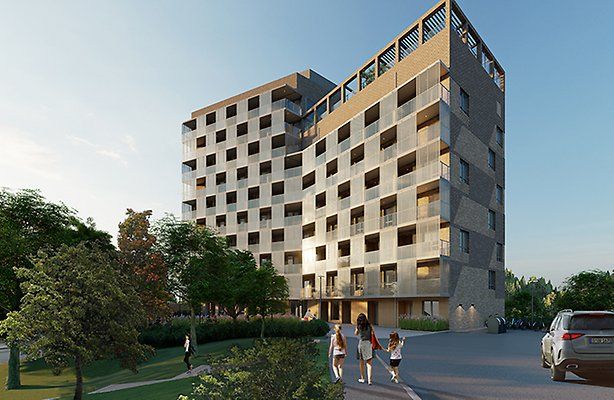 Bild av ett modernt flerfamiljshus med stora fönster och balkonger. Tre personer går på gångvägen framför byggnaden.