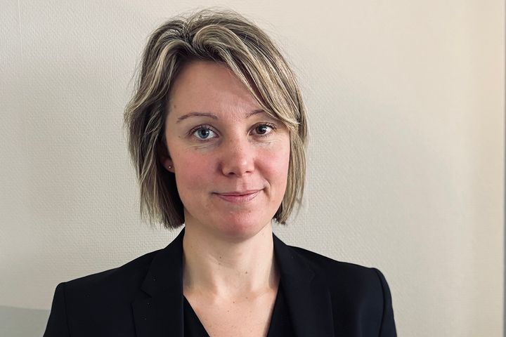 En närbild på en kvinna med ljust hår som står mot en vägg.