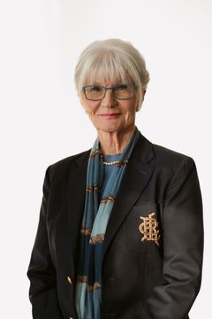 En kvinna i glasögon och kavaj, med blå halsduk.