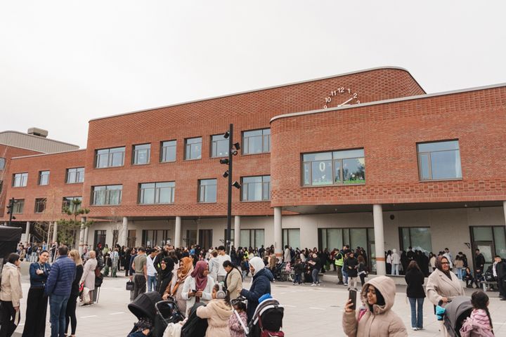 En%20stor%20grupp%20m%E4nniskor%20k%F6ar%20utanf%F6r%20en%20tegelbyggnad.