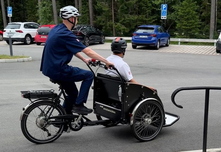 Två personer cyklar på en trehjulig cykel utomhus.