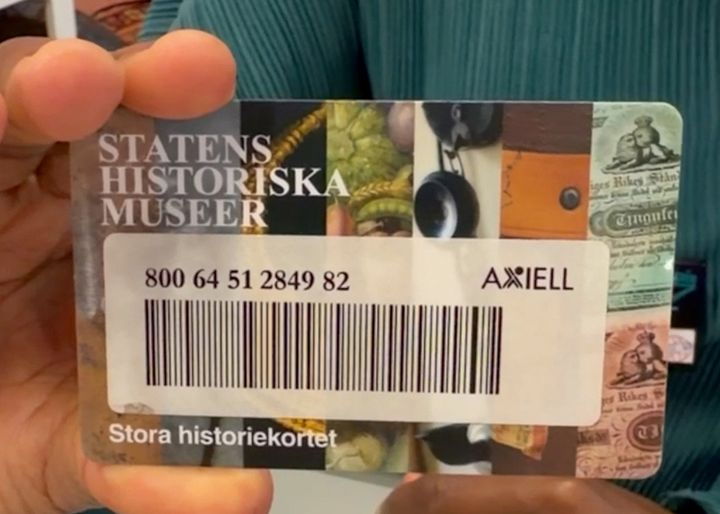 Person håller i ett lånekort för Statens historiska museer med ett streckkod och texten "Stora historiekortet".