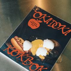 Bild av kokboken "Okidoki Kokbok" med en äggula och krossade äggskal ovanpå omslaget.