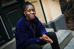 Kvinna sitter på en trappa och ler.