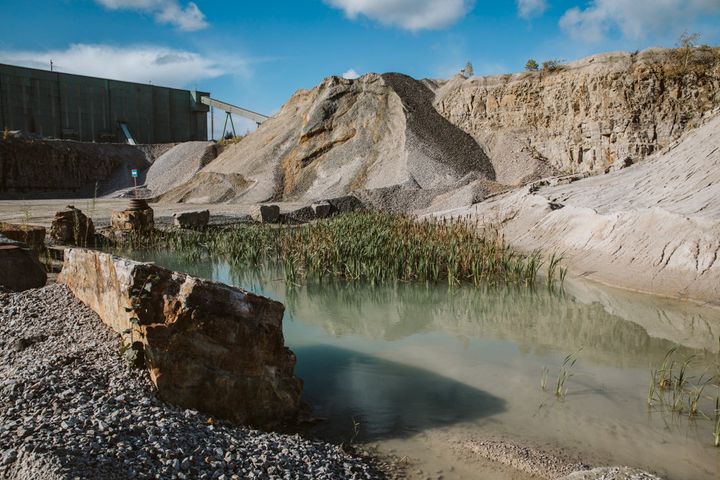 En bergtäkt med stenmassor och en mindre vattenansamling.
