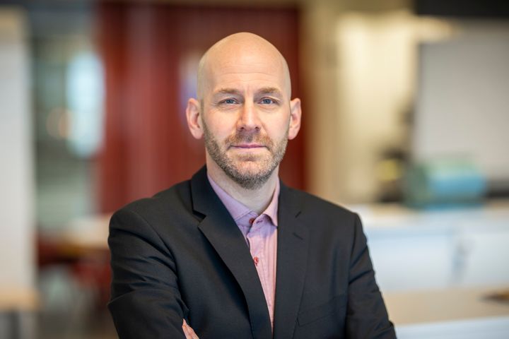 Man i kontorsmiljö som tittar in i kameran.