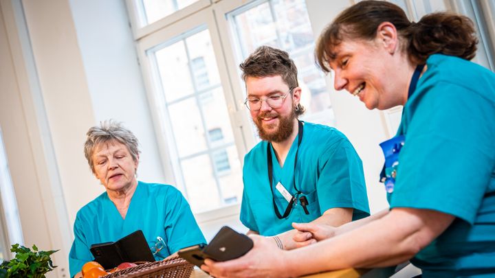 Vårdpersonal vid fikabord, ser glada ut.