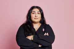 Adine Samadi med armarna i kors mot rosa bakgrund