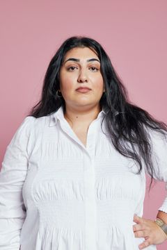 Roks ordförande Adine Samadi framför rosa bakgrund med handen i sidan.