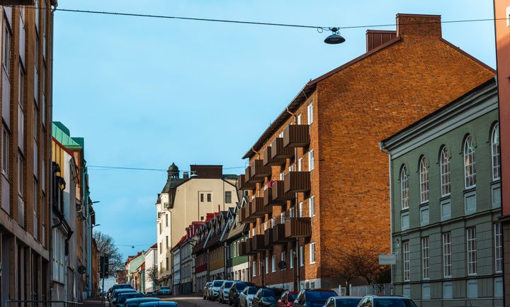 Gata med parkerade bilar och flerfamiljshus på båda sidor.