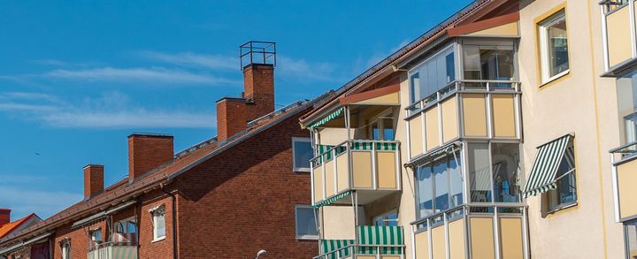 Flerfamiljshus i tegel med balkonger under en blå himmel.