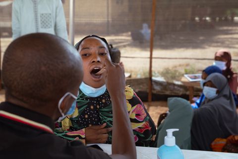 En man använder en träspatel för att undersöka en patient med misstänkt difteri i Nigeria.