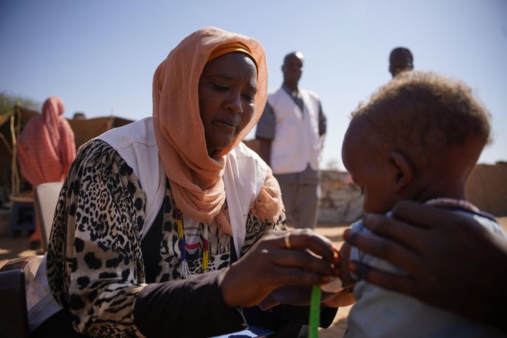 En medarbetare från Läkare Utan Gränser undersöker ett litet barn i Zamzam-lägret i norra Darfur, Sudan.