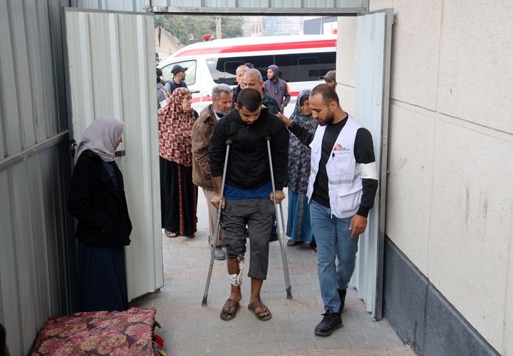 En man som går på kryckor får hjälp av en medarbetare från Läkare Utan Gränser i Gaza.