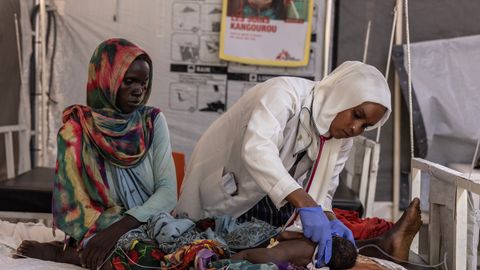 Läkaren Faiza Hamed Hangata står lutad över ett barn som hon undersöker på Läkare Utan Gränsers sjukhus i Metche, i östra Tchad.