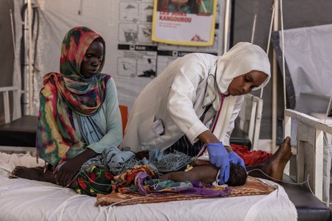 Läkaren Faiza Hamed Hangata står lutad över ett barn som hon undersöker på Läkare Utan Gränsers sjukhus i Metche, i östra Tchad.