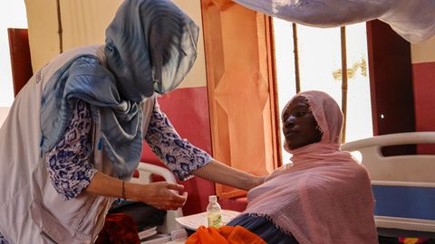 Anhar Hassan Mohammed Omar ligger i en sjukhussäng på ett sjukhus i Nyala, södra Darfur, Sudan. Breid henne står en medarbetade från Läkare Utan Gränser.