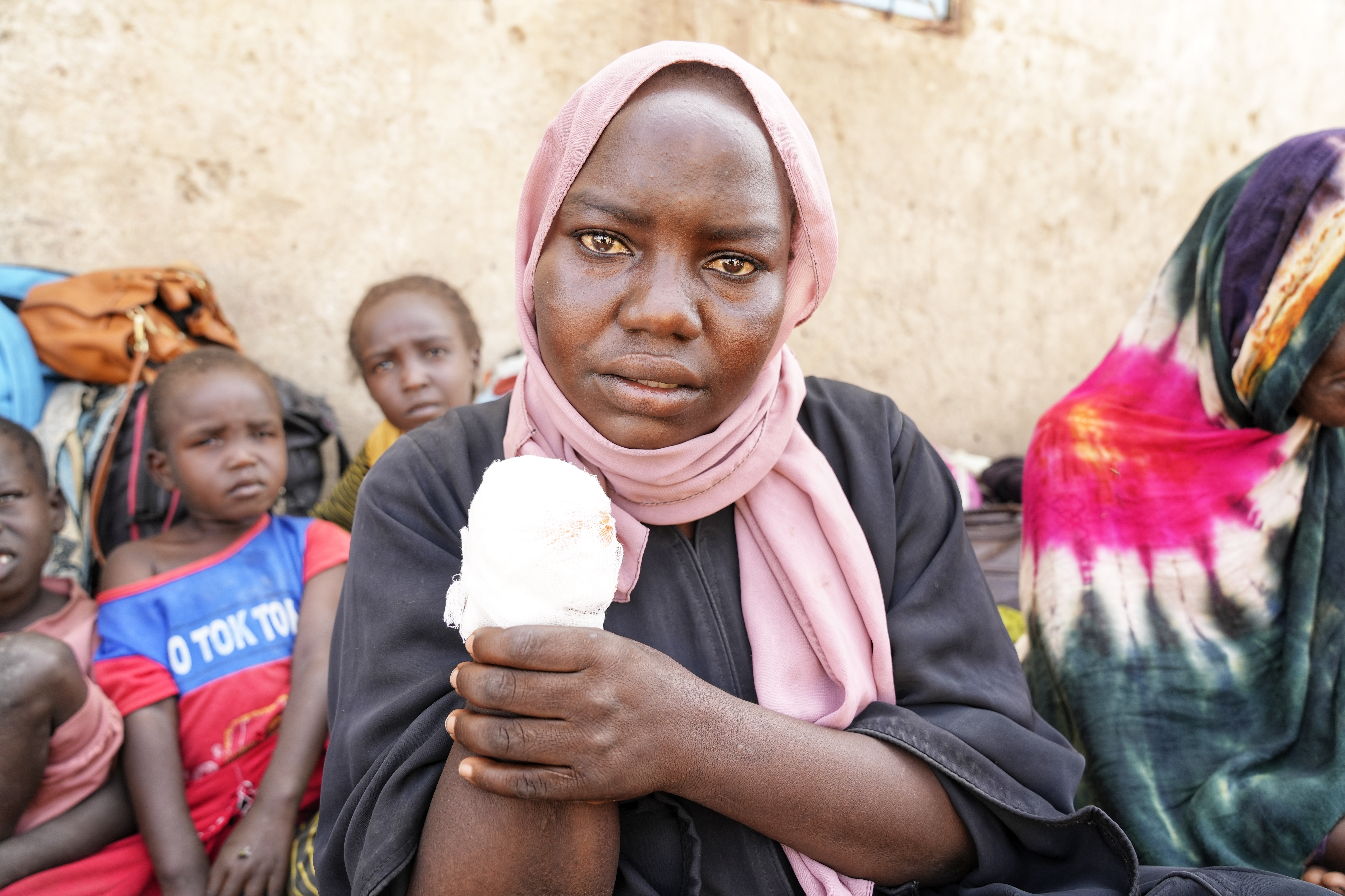 Al Touma Adam Abdullah Tour håller upp en arm i bandage. Hon fick sin hand aputerad efter att hon skadades i ett bombanfall mot marknaden i delstaten White Nile.