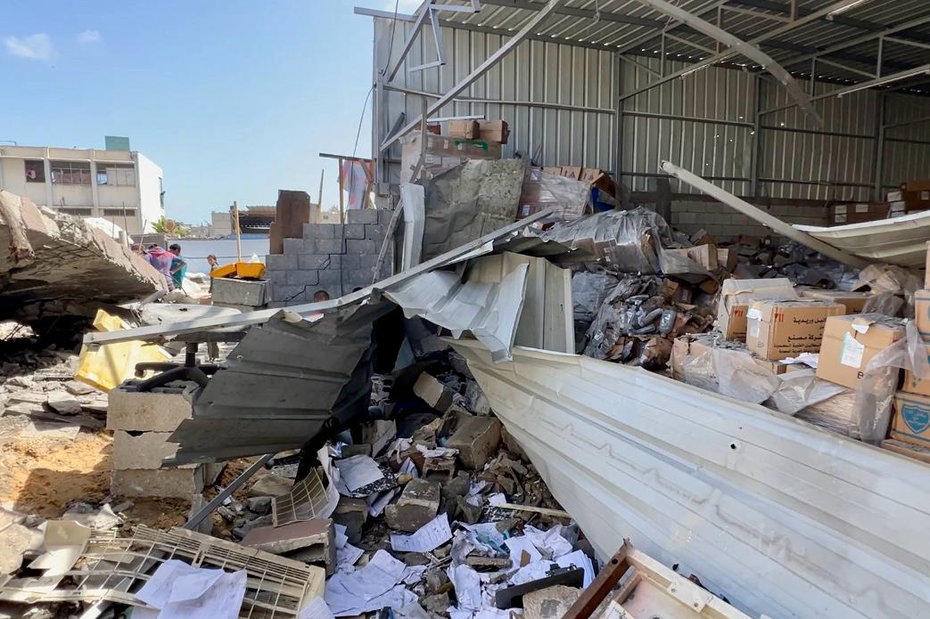 Ett förstörd lager där väggen är borta och lådor ligger utspridda. Den 19 maj träffades området runt Nasser-sjukhuset i en attack, endast 100 meter från intensivvårdsavdelningen och vårdavdelningen som båda drivs av Läkare Utan Gränser. Attacken förstörde också delar av ett apotek.