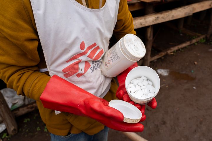 En medarbetare från Läkare Utan Gränser håller upp en burk med reningstabletter som används för att förse befolkningen i Lomera, en gruvstad i Sydkivu, med rent dricksvatten.