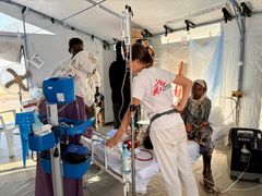 ett sjukvårdsteam arbetar vid en säng i ett tältsjukhus