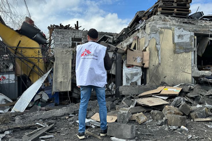 Läkare Utan Gränsers medarbetare Oleksandr Cherniavskyi står med ryggen mote kameran och ser över omfattningen efter en attack mot Läkare Utan Gränser i Pokrovsk, Ukraina, i april 2023.