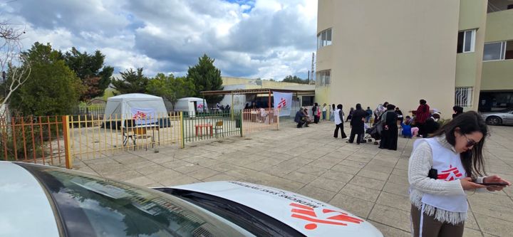 En mobil klinik från Läkare Utan Gränser i Saida, södra Libanon. En medarbetare står framför en bil. Bakom henne syns flera tält från Läkare Utan Gränser.