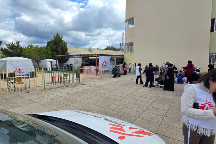 En mobil klinik från Läkare Utan Gränser i Saida, södra Libanon. En medarbetare står framför en bil. Bakom henne syns flera tält från Läkare Utan Gränser.