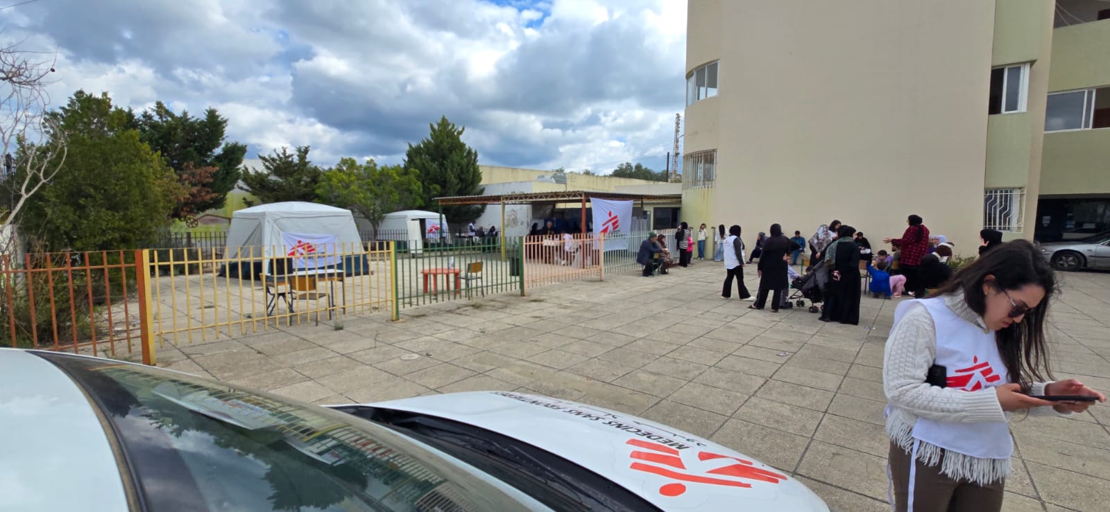 En mobil klinik från Läkare Utan Gränser i Saida, södra Libanon. En medarbetare står framför en bil. Bakom henne syns flera tält från Läkare Utan Gränser.