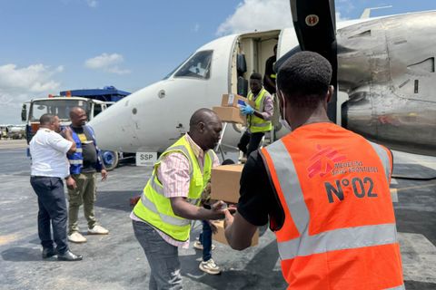 En man lastar av lådor med medicinsk utrustning på Bunia flygplats, Kongo-Kinshasa, och räcker en låda till en annan man. Utrustningen ska användas för att bekämpa ebola i det pågående utbrottet.