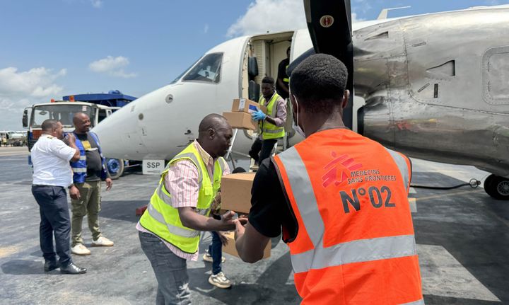En man lastar av lådor med medicinsk utrustning på Bunia flygplats, Kongo-Kinshasa, och räcker en låda till en annan man. Utrustningen ska användas för att bekämpa ebola i det pågående utbrottet.