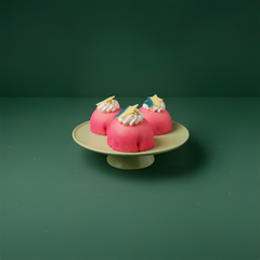 Tre rosa bakelser med grädde och dekor på ett grönt fat.