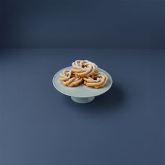 En vit skål med krispiga struvor mot en mörk bakgrund.