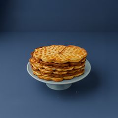 En hög med kärnmjölksvåfflor på ett fat mot en blå bakgrund.