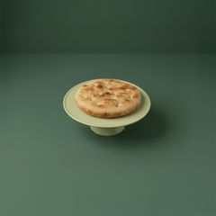 En Dalslandskaka på ett grönt fat mot en grön bakgrund.