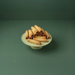 En hög med gyllene rullrån på ett fat mot en grön bakgrund.