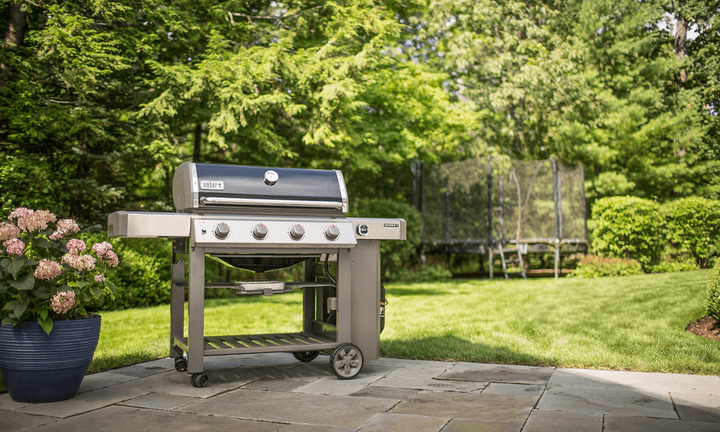 Grill på en solig uteplats i en grönskande trädgård.