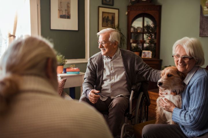 Äldre sitter inomhus med en hund.