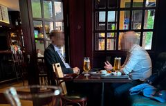 Två personer sitter vid ett bord i restaurangmiljö. Ansiktena är blurrade.
