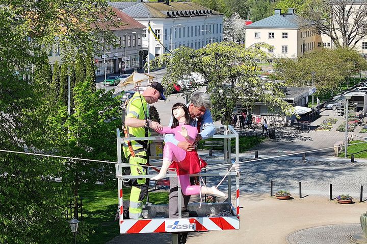 Den färgglada ballerinan monteras på linan högt uppe i luften av två personer i en skylift.