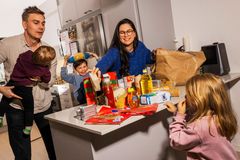 Två föräldrar och deras barn är vid en köksbänk full av matvaror.