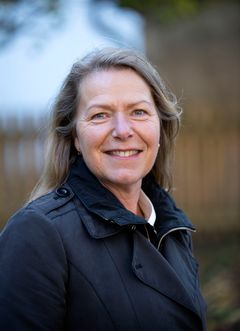 Glad kvinna utomhus i mörk jacka