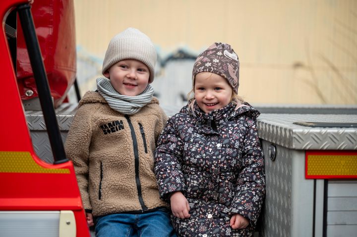 Två glada barn står på en brandbil.